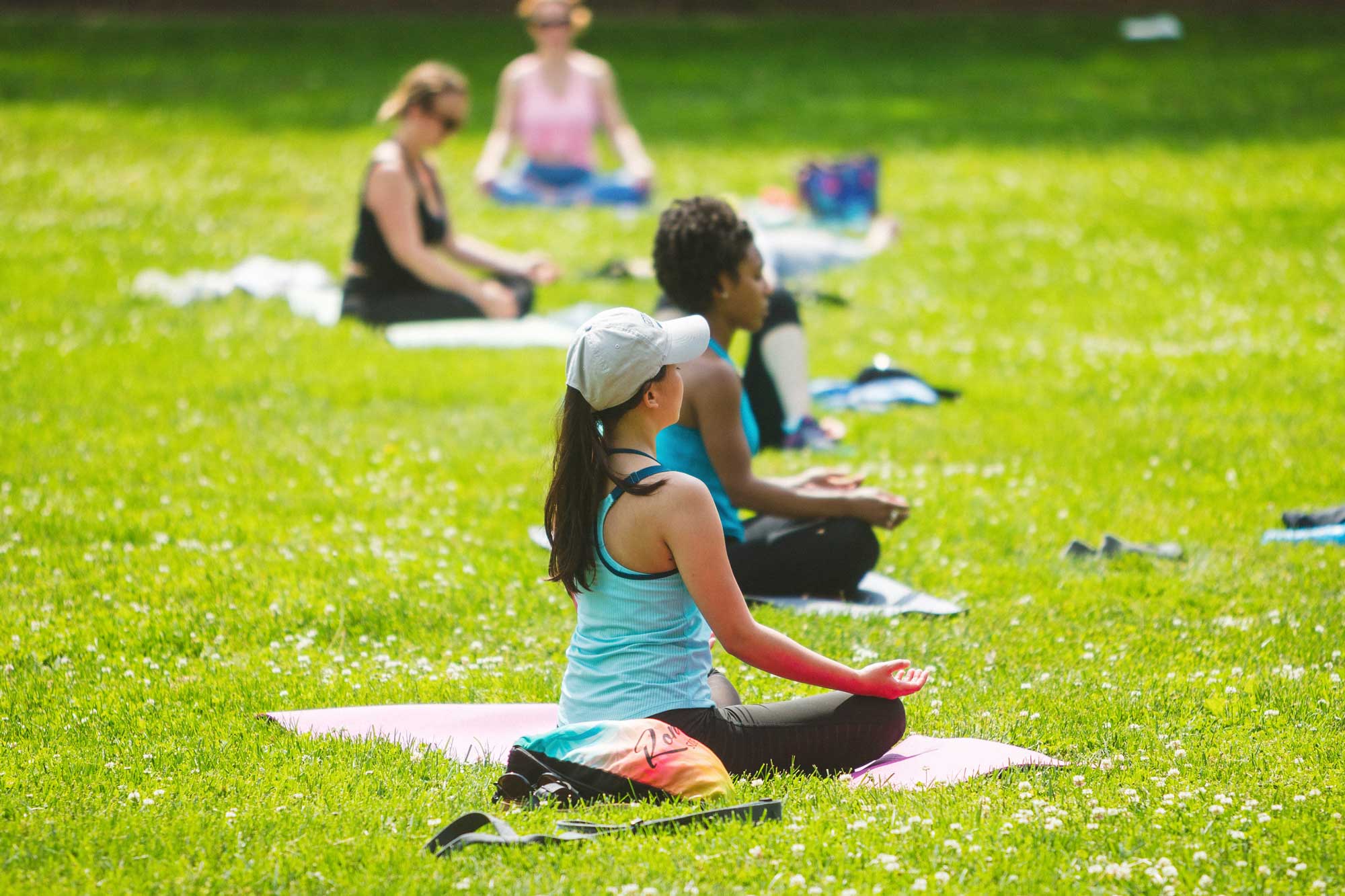 People do yoga outside in a grassy area.