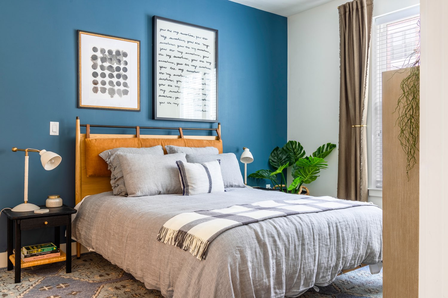 A bedroom with a bold blue wall behind the bed.