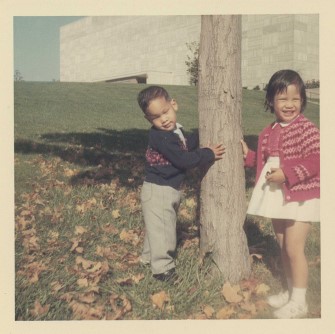 An antique photo of two children next to a tree.