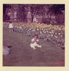 An antique photo of a child in front of a field of flowers.