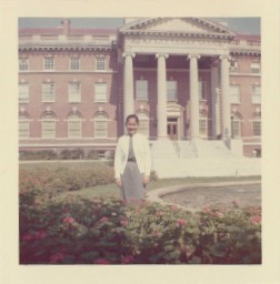 An antique photo of a woman in front of a large building.