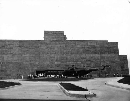Black and white image of an army plane in front of a building.