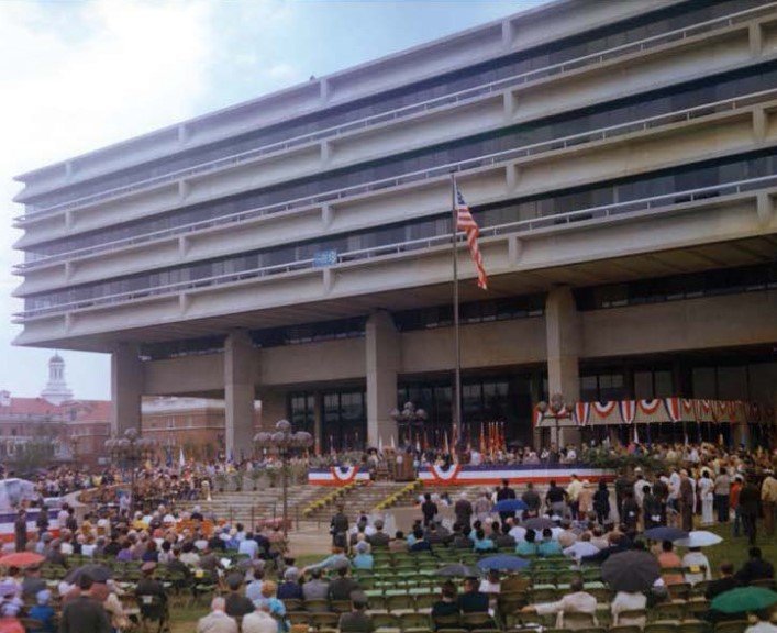 An antique photo of a conference in front of a building.